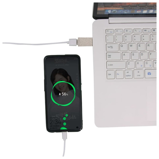A USB data blocker in wheat straw material connects a smartphone to a laptop, displaying a charging indicator.