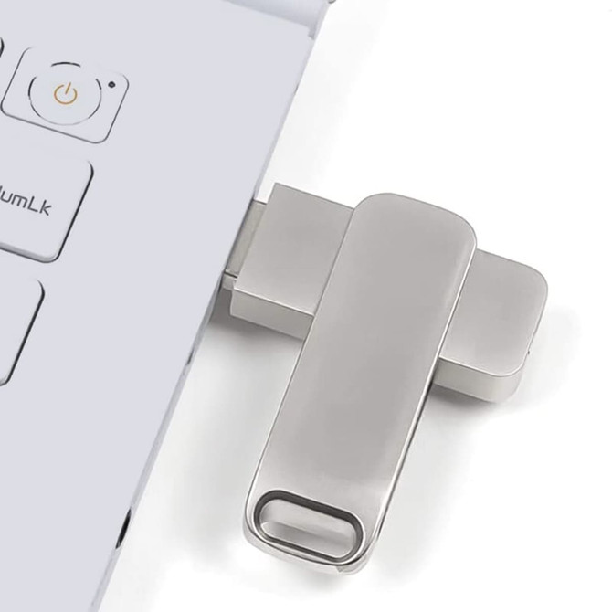 A silver Executive Twist Flash Drive is plugged into a laptop, positioned beside the keyboard.