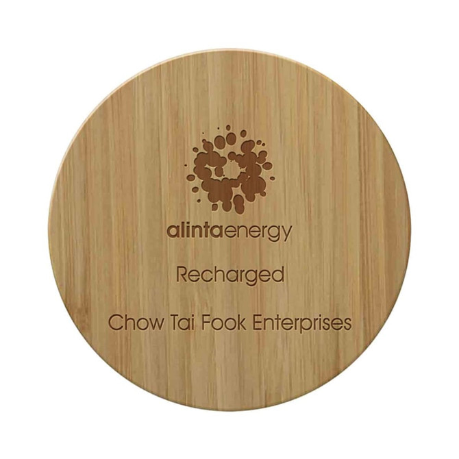 A round bamboo wireless charger with a wooden texture and a logo. It features engraved text.