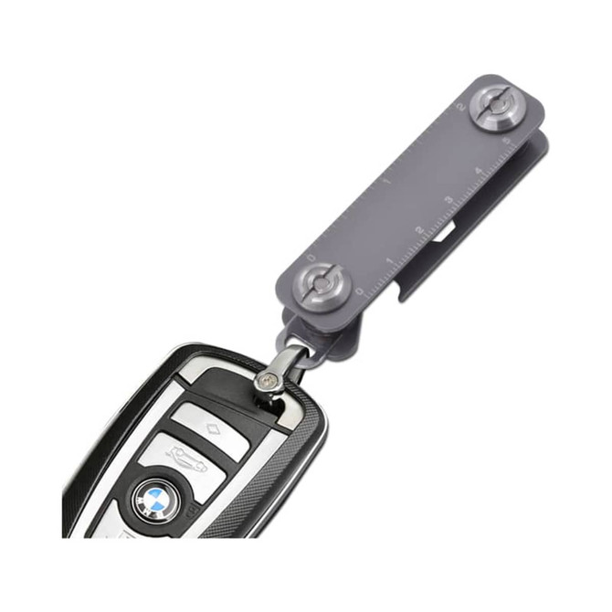 A grey Keyper Case with a keyring attachment, featuring a measuring scale and a sleek design for holding keys.