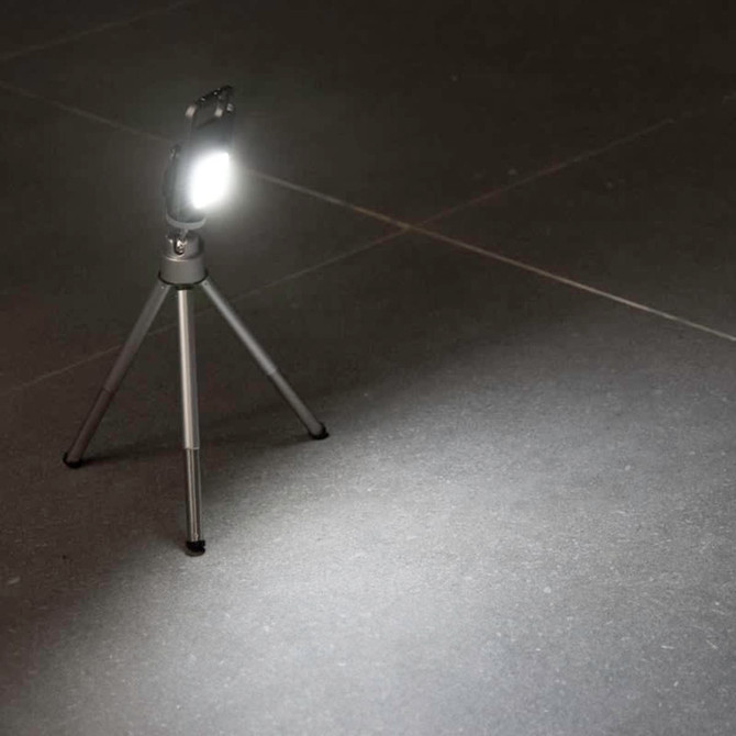 A multi-tool featuring a COB LED light on a small tripod, with a sleek design in black and silver.