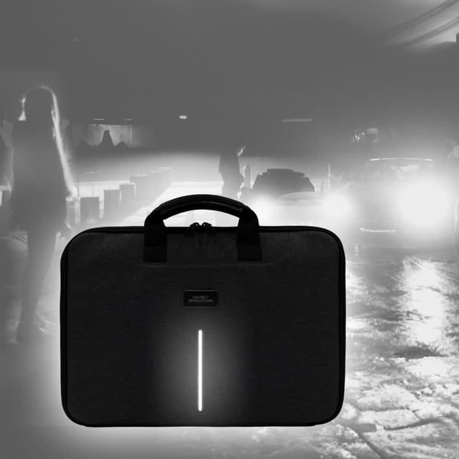 A black laptop case with a handle and a reflective strip, set against a blurred nighttime background.