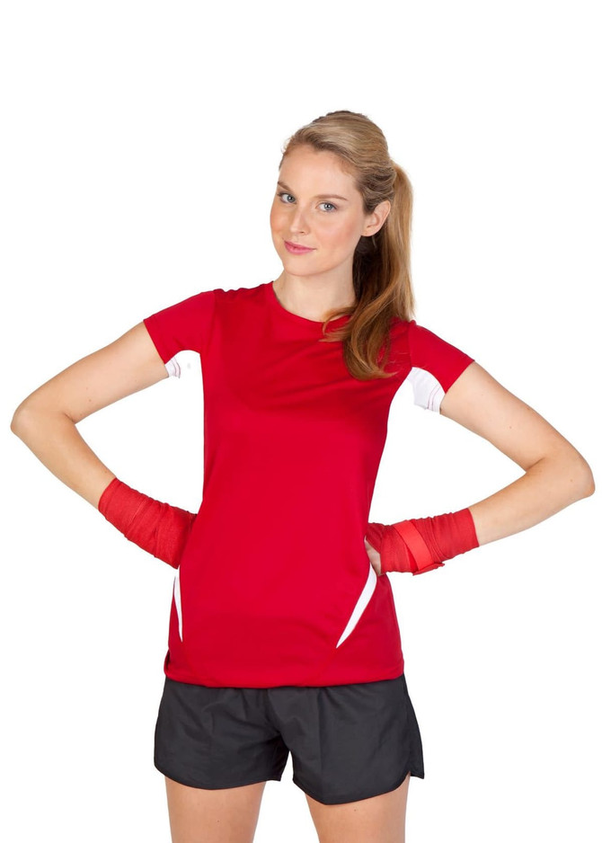 A woman in a red and white short-sleeved T-shirt flexes her arms, wearing black shorts and red hand wraps.