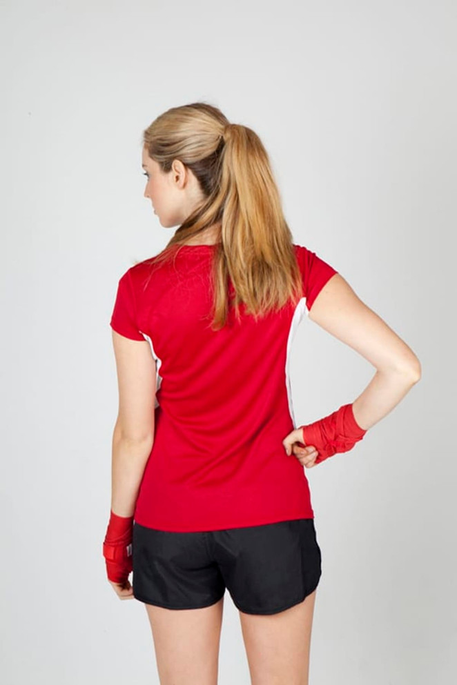 A red women's T-shirt with short sleeves, featuring white accents and a logo, paired with black shorts.