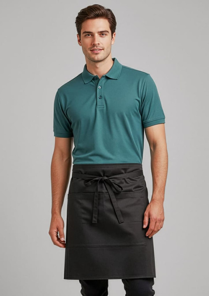 A man wearing a teal polo shirt and a black short-waisted apron. The apron has a tie closure and features a logo.