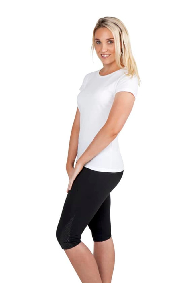 A woman poses in a fitted white slim fit tee paired with black leggings, showcasing a clean and casual look.