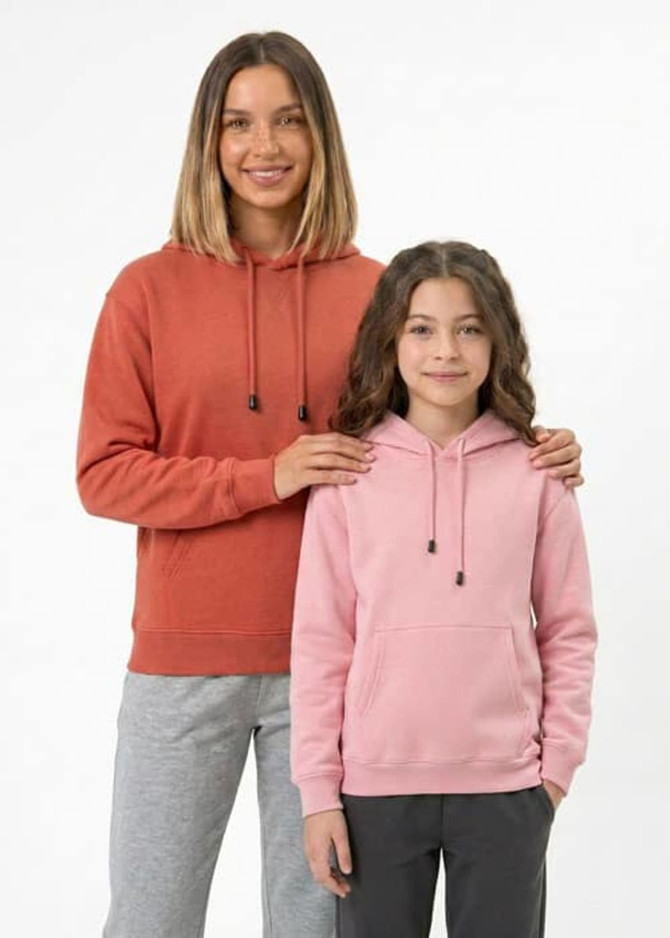 A woman in an orange hoodie and a girl in a pink hoodie, both with kangaroo pockets, standing together.