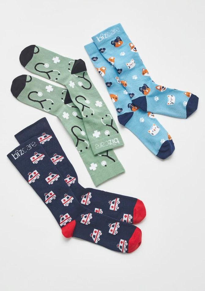 Unisex Happy Feet Comfort Socks in green with medical symbols, blue with animals, and navy with emergency vehicles.