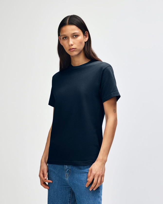 A heavyweight cotton unisex t-shirt in black, displayed on a model with straight hair and denim jeans.
