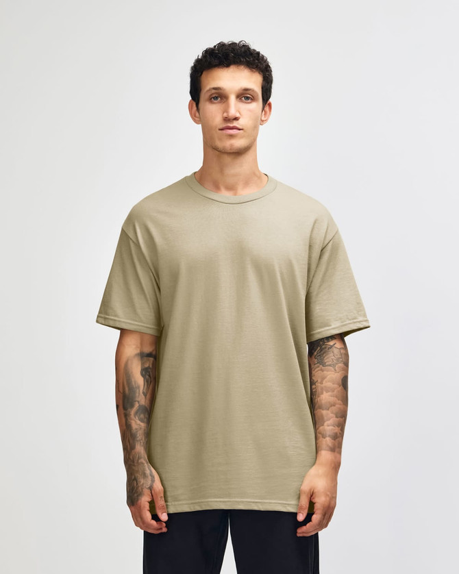 A heavyweight unisex T-shirt in a muted olive green colour, displayed on a model with curly hair.