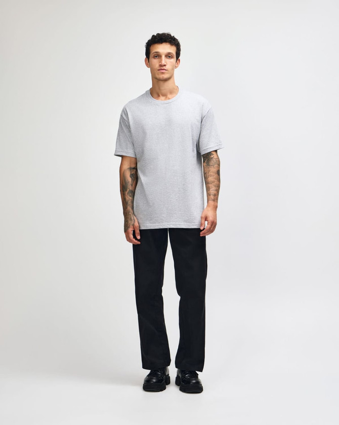 A plain grey heavyweight cotton unisex T-shirt displayed on a model, paired with olive green trousers.