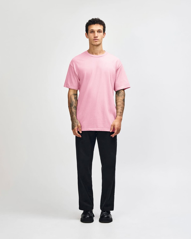 A heavyweight cotton unisex T-shirt in pink, paired with light blue jeans and black sneakers, displayed on a male model.