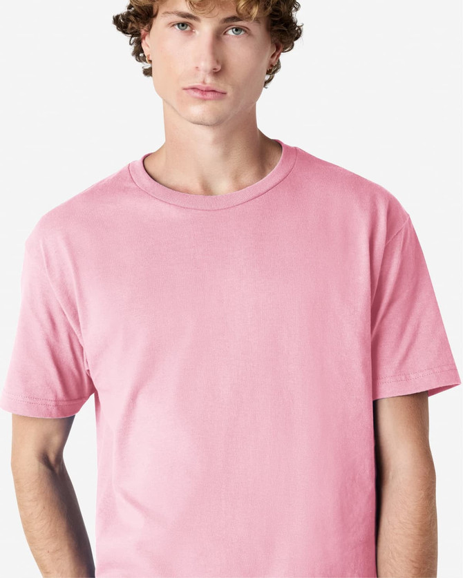 A unisex heavyweight cotton t-shirt in pink, featuring a round neckline and short sleeves. It has a logo.
