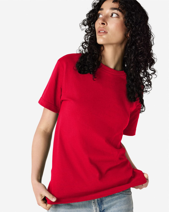 A red heavyweight cotton unisex T-shirt displayed on a model with curly hair. The shirt has a logo on it.