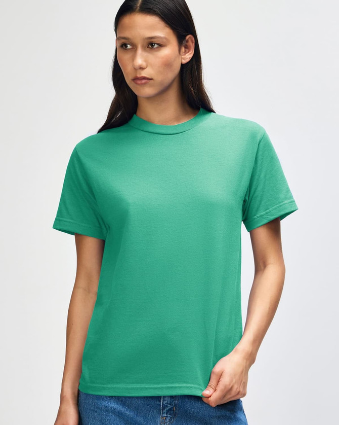 A green heavyweight cotton unisex T-shirt is displayed on a model with curly hair, featuring a simple design and a logo.