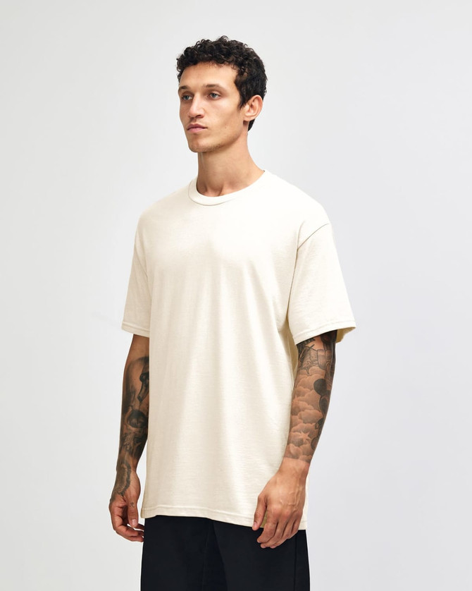 A heavyweight cotton unisex t-shirt in cream, displayed on a model with a neutral background.