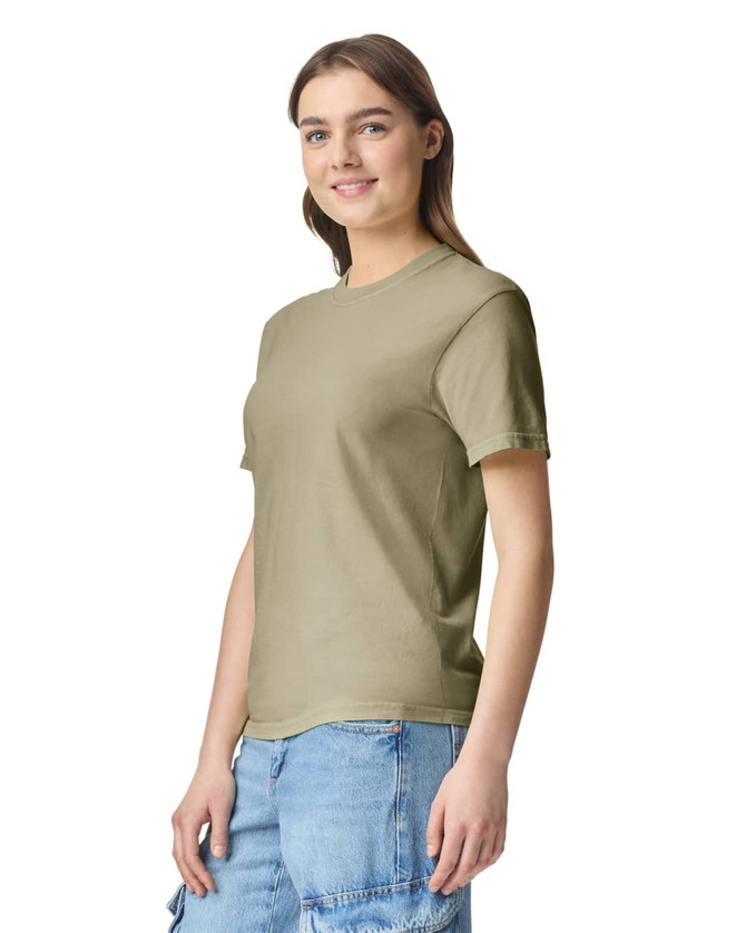 A woman stands wearing an olive green heavyweight T-shirt with short sleeves. The shirt has a logo.