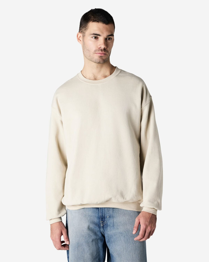 A beige Gildan Heavy Blend adult crewneck sweatshirt displayed on a model, featuring a relaxed fit and long sleeves.