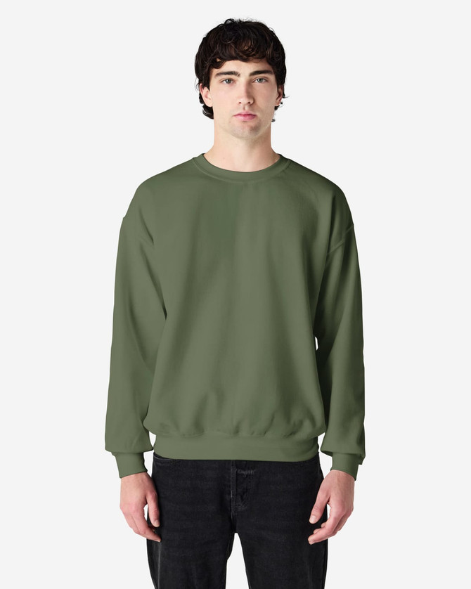 A green crewneck sweatshirt worn by a person, featuring a relaxed fit and long sleeves. It has a logo on the sleeve.
