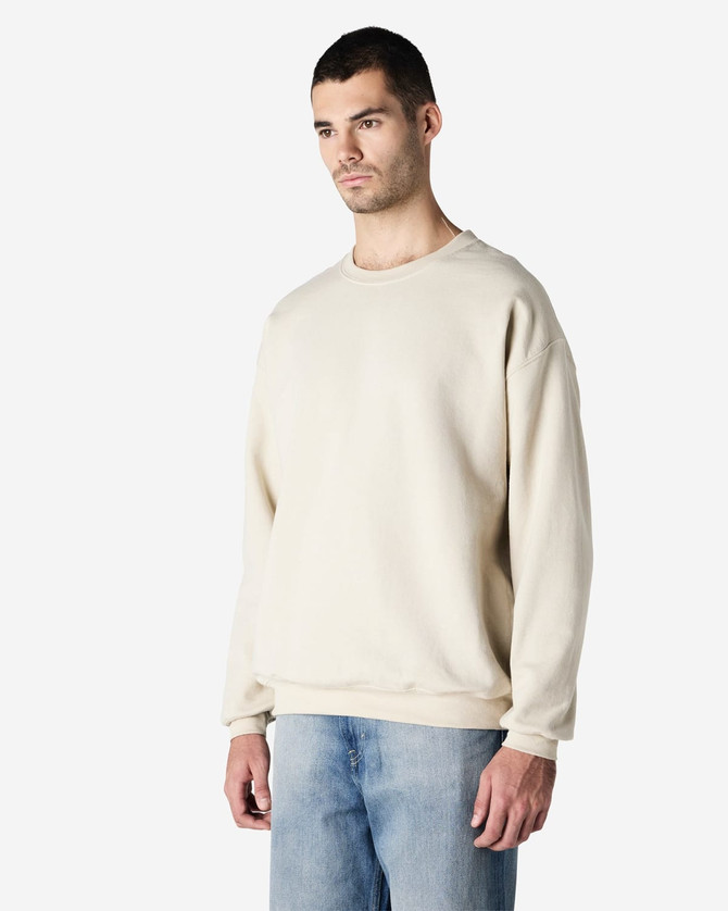 A beige Gildan Heavy Blend adult crewneck sweatshirt displayed on a model, with a plain design and relaxed fit.