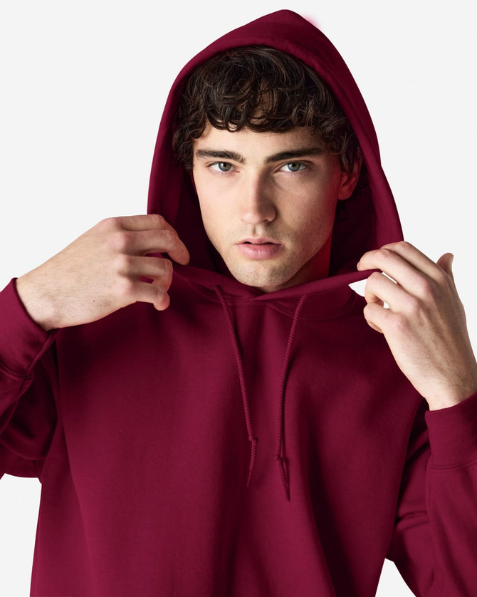 A hooded sweatshirt in a deep burgundy colour, featuring a drawstring hood and an individual adjusting the neckline.