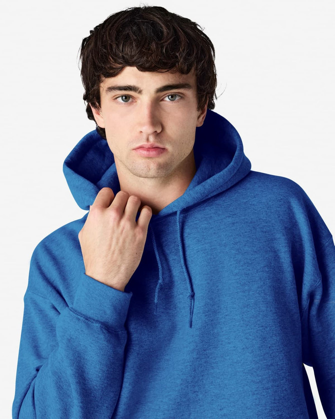 A blue Gildan Heavy Blend adult hooded sweatshirt with a drawstring hood and a model adjusting the neckline.