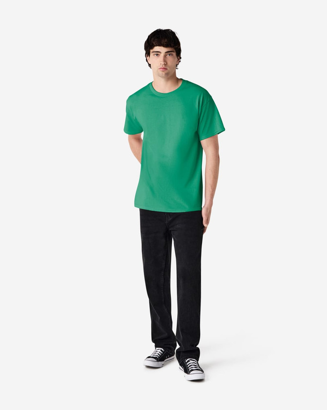 A green Gildan Ultra Cotton adult T-shirt displayed on a model, paired with black pants and sneakers.