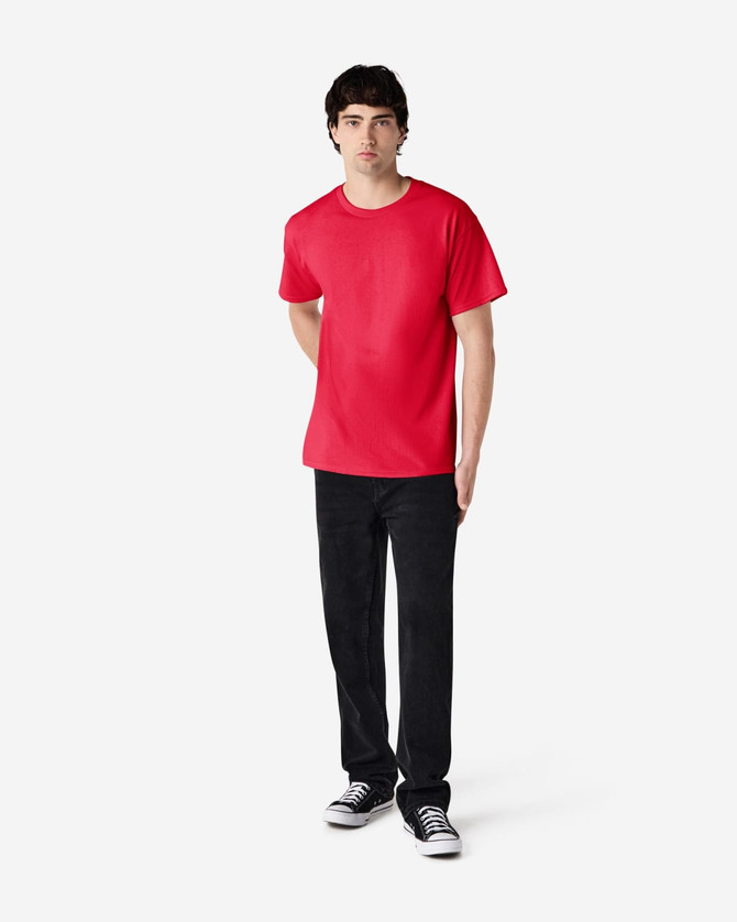A red Gildan Ultra Cotton adult T-shirt displayed on a model wearing black pants and sneakers. The shirt has a logo.