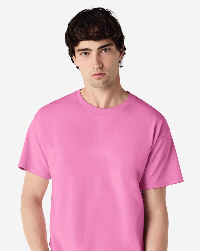 A pink Gildan Ultra Cotton adult T-shirt displayed by a model, featuring a plain design and a logo.