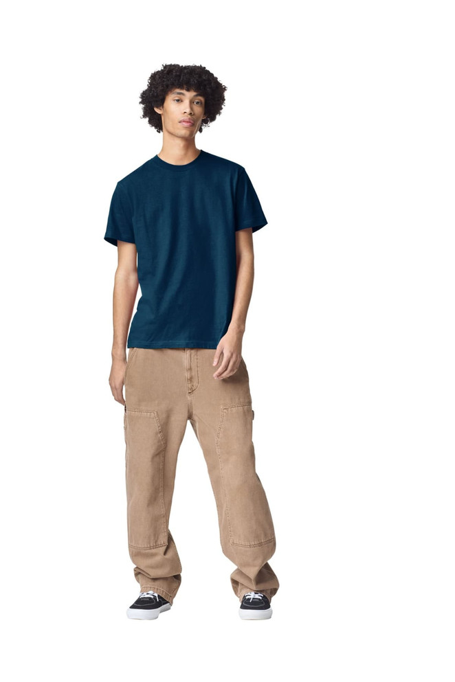 A model wearing a navy unisex fine jersey short sleeve t-shirt and tan wide-leg pants. The t-shirt has a logo.