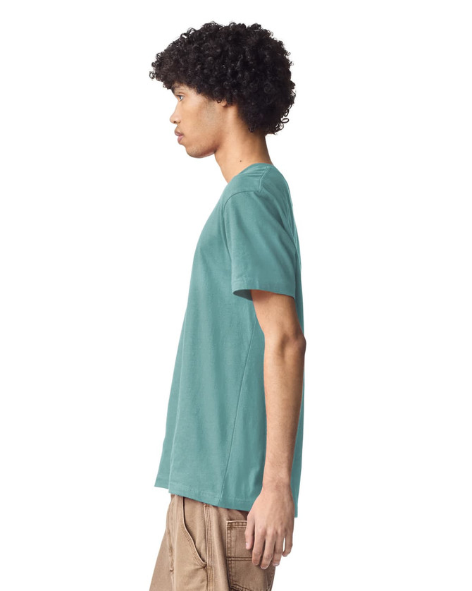 A unisex short sleeve T-shirt in teal, featuring a logo on the front, displayed from the side.