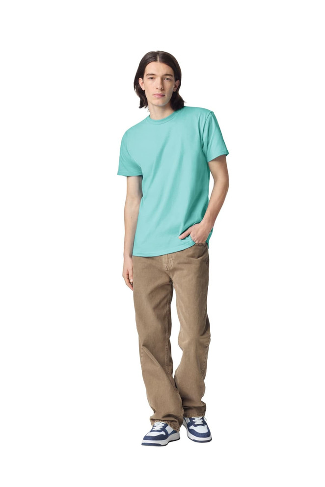 A model wearing a turquoise unisex fine jersey short sleeve t-shirt paired with khaki pants. The shirt has a logo.