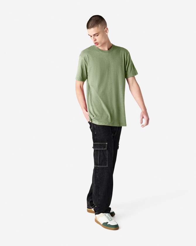 A model wearing a green unisex short sleeve T-shirt and black cargo pants, standing in a neutral setting.