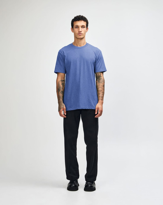 A unisex CVC short sleeve T-shirt in blue, paired with black cargo pants and casual footwear.