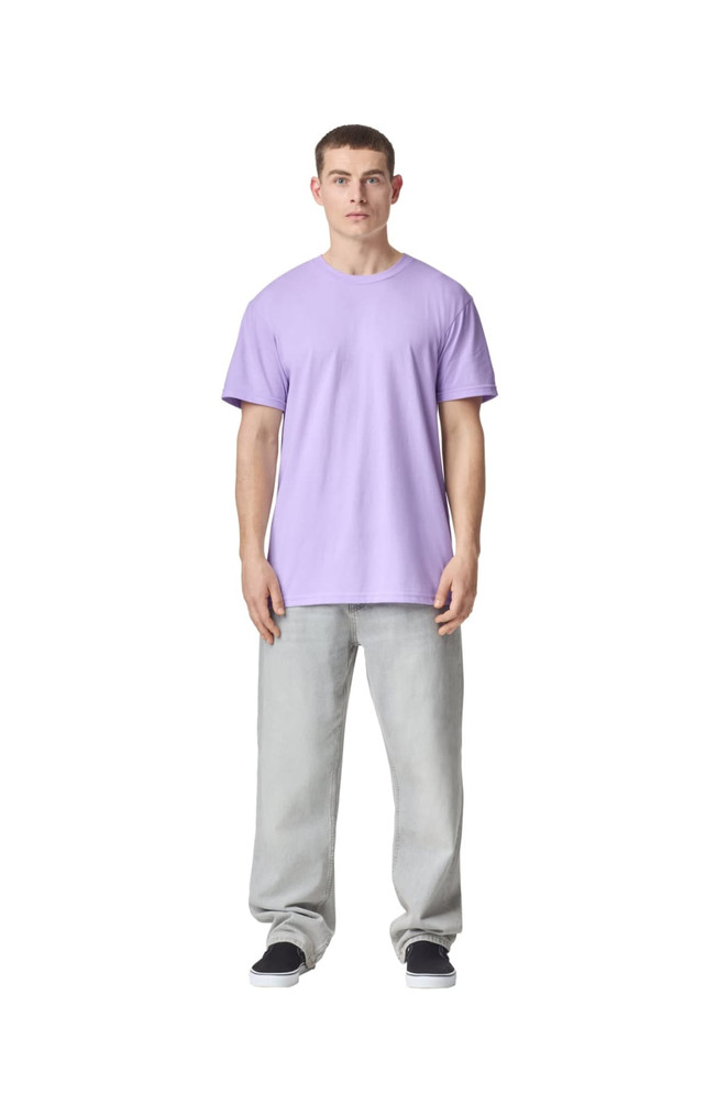 A model stands in a lavender unisex CVC short sleeve T-shirt paired with light grey trousers. The shirt has a logo.
