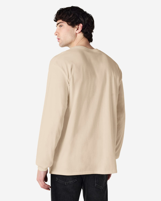 A man wearing a beige Gildan Ultra Cotton long sleeve T-shirt, viewed from the back. The shirt features a logo.