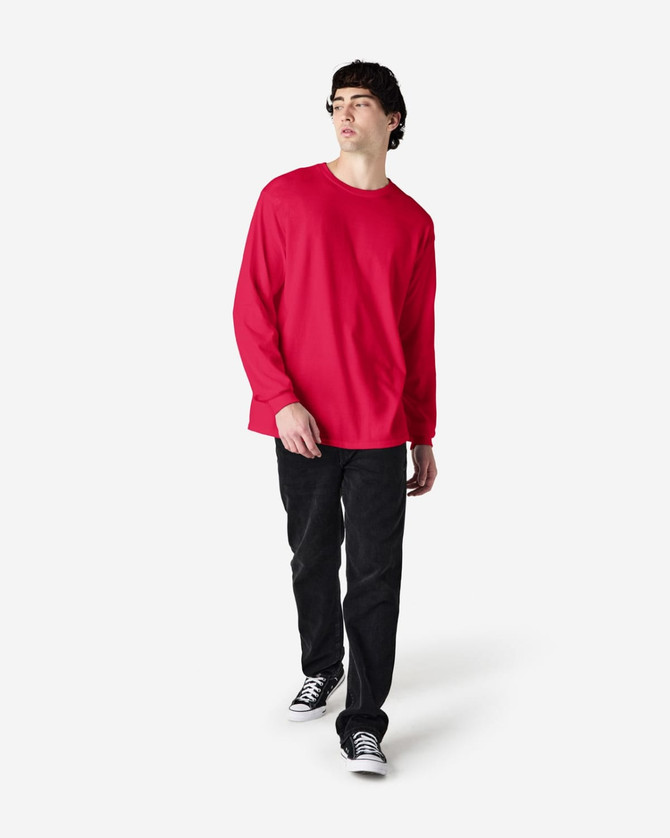 A male model wears a red long-sleeve t-shirt paired with black jeans and sneakers. The shirt features a logo.