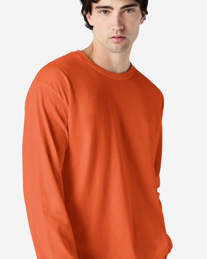 An orange long sleeve T-shirt on a model, featuring a simple design and a logo on the shirt.