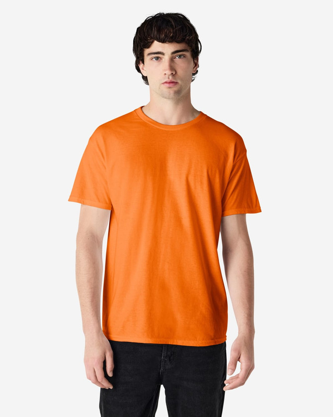 An orange Gildan Heavy Cotton Adult T-Shirt worn by a model with a plain background. The shirt has a logo.