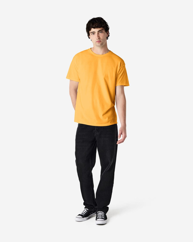 A man wearing a bright yellow Gildan Heavy Cotton T-shirt and black pants, standing with a neutral expression.