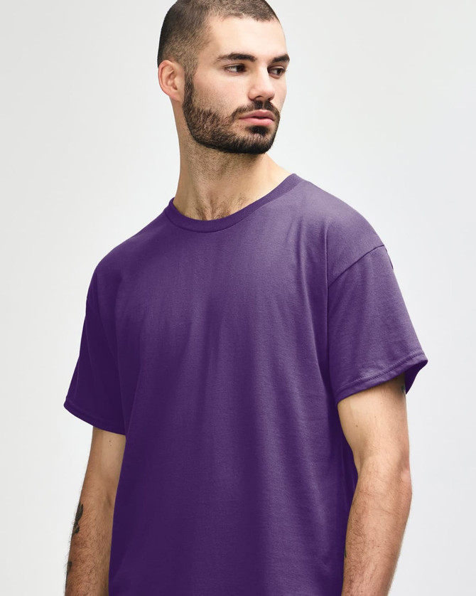 A purple Gildan Heavy Cotton adult t-shirt, displayed on a model with hands behind their back.
