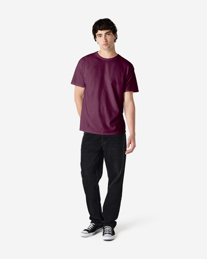 A maroon Gildan Heavy Cotton Adult T-Shirt displayed on a model wearing black jeans and sneakers.