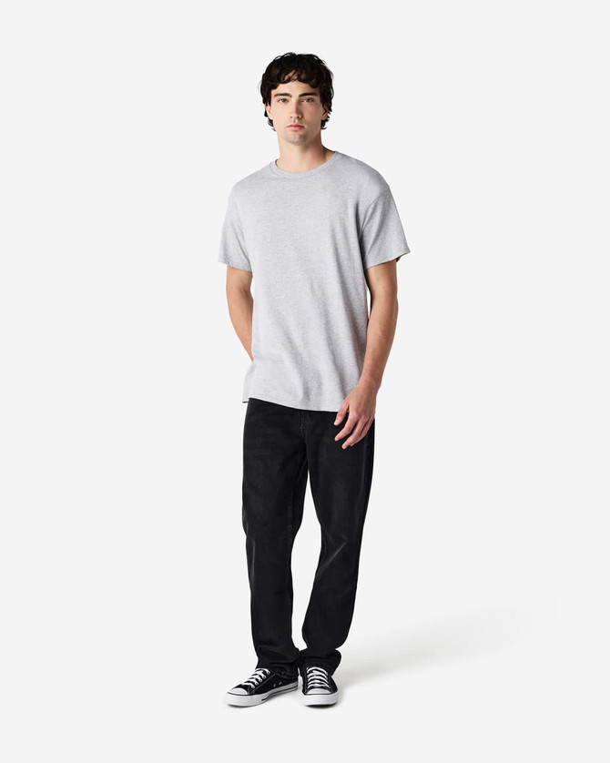 A grey Gildan Heavy Cotton adult T-shirt displayed on a male model wearing black pants and sneakers.