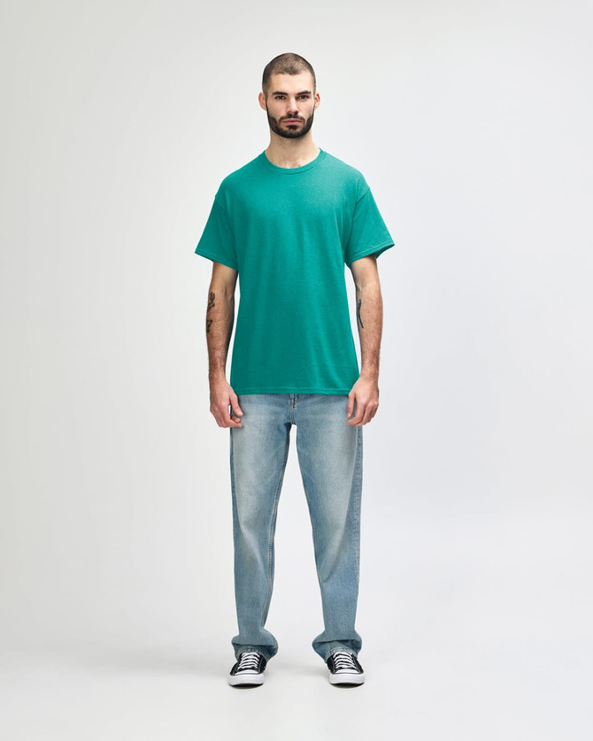 A turquoise Gildan Heavy Cotton Adult T-Shirt displayed on a male model, paired with black jeans and sneakers.