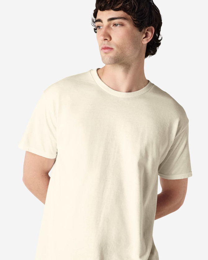 A cream-coloured Gildan Heavy Cotton adult T-shirt, displayed on a model with short curly hair.