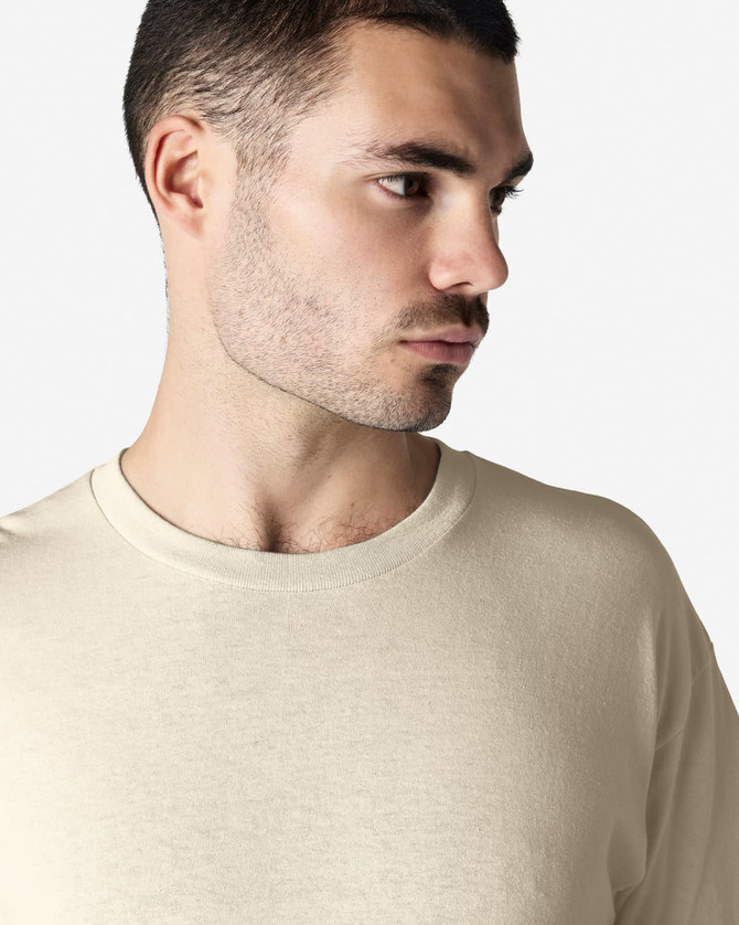 A cream-coloured Gildan Heavy Cotton adult T-shirt, displayed on a model with short curly hair.