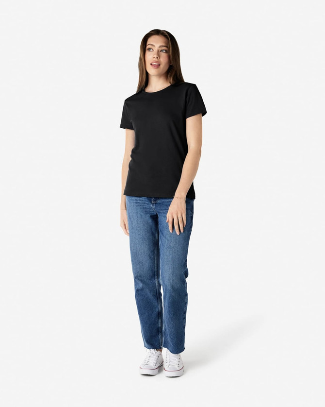 A black ladies' t-shirt displayed on a model, paired with blue jeans and white shoes, featuring a logo.