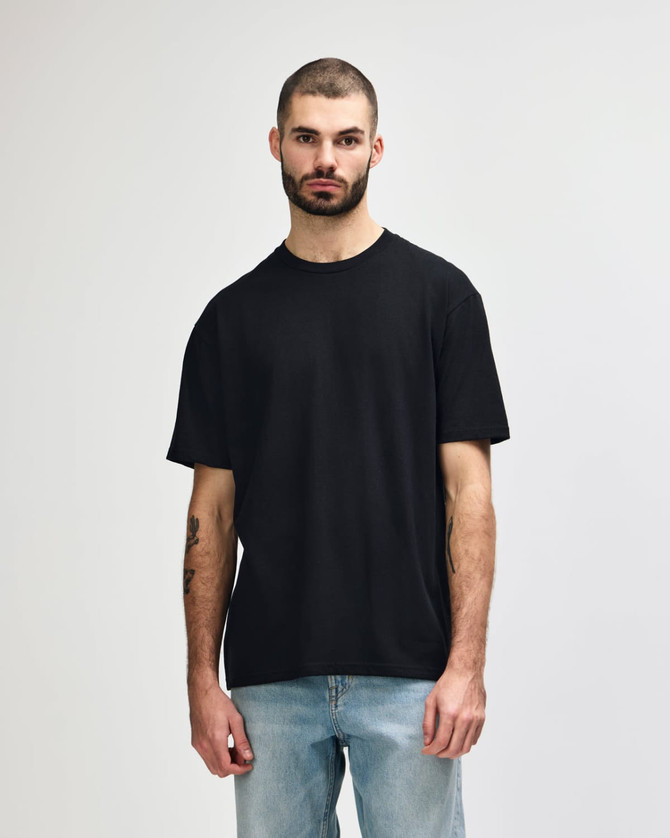 A black Gildan Softstyle adult midweight T-shirt displayed on a model, featuring a simple design and no visible logo.