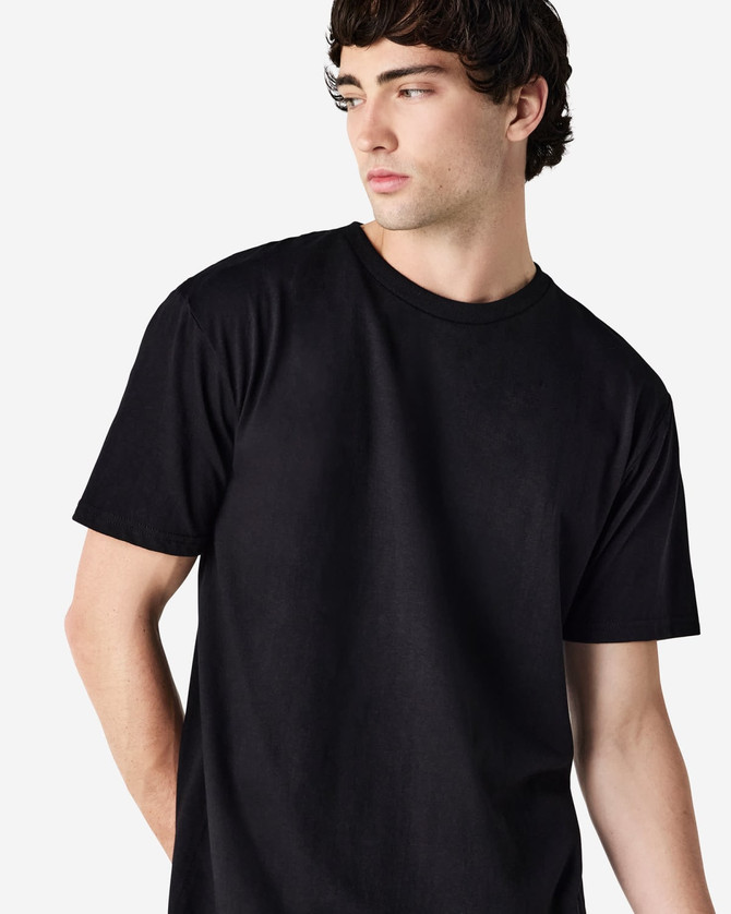 A black Gildan Softstyle adult midweight T-shirt displayed on a model, featuring a simple design and relaxed fit.