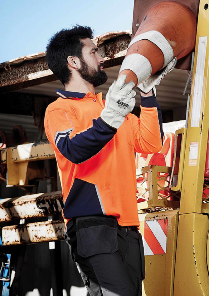 A long sleeve polo in high visibility orange and navy, featuring a logo, worn by a person handling safety equipment.